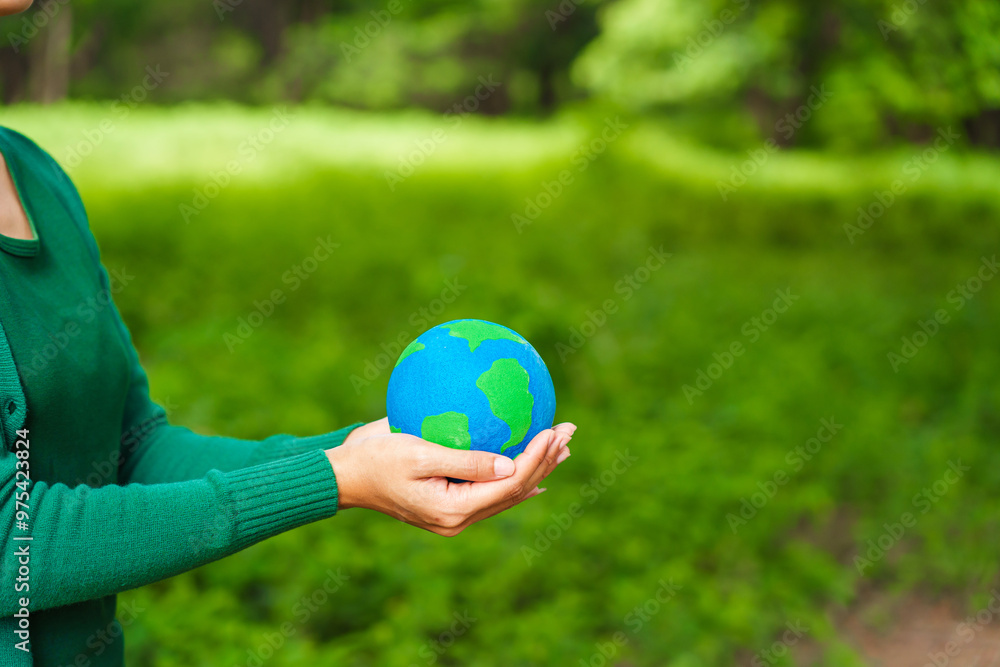 Forest conservationist holds small globe in hands, symbolizing global responsibility for protecting planet. Standing outdoors in green park, sustainability, commitment to achieving net-zero impact. Forest conservationist holds small globe in hands, symbolizing global responsibility for protecting planet. Standing outdoors in green park, sustainability, commitment to achieving net-zero impact.