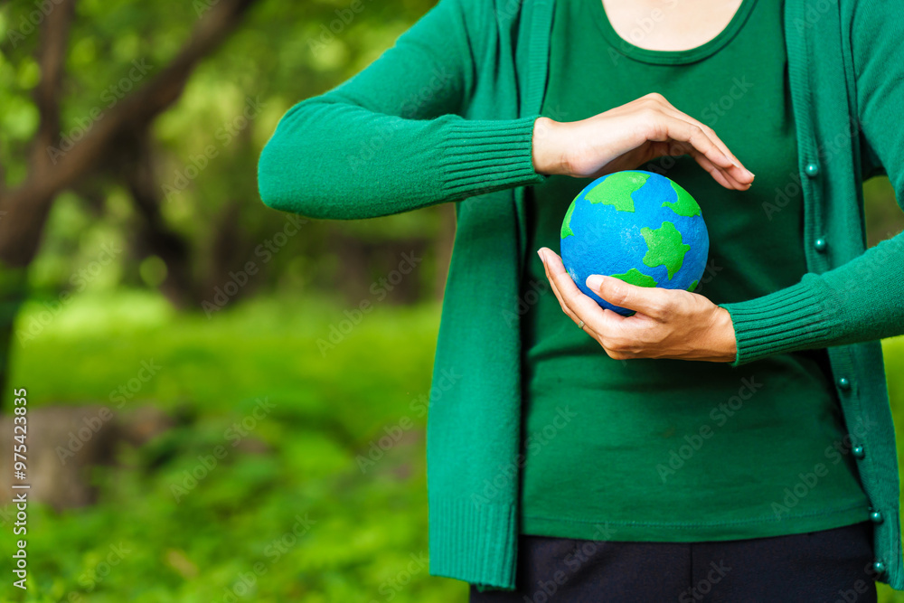 Forest conservationist holds small globe in hands, symbolizing global responsibility for protecting planet. Standing outdoors in green park, sustainability, commitment to achieving net-zero impact. Forest conservationist holds small globe in hands, symbolizing global responsibility for protecting planet. Standing outdoors in green park, sustainability, commitment to achieving net-zero impact.
