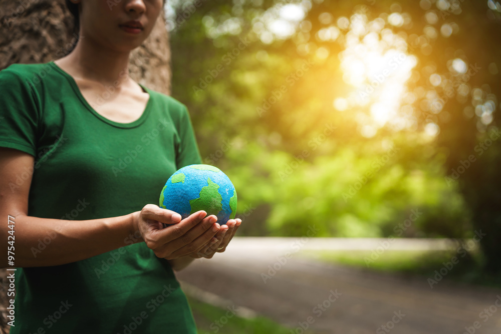 Forest conservationist holds small globe in hands, symbolizing global responsibility for protecting planet. Standing outdoors in green park, sustainability, commitment to achieving net-zero impact. Forest conservationist holds small globe in hands, symbolizing global responsibility for protecting planet. Standing outdoors in green park, sustainability, commitment to achieving net-zero impact.