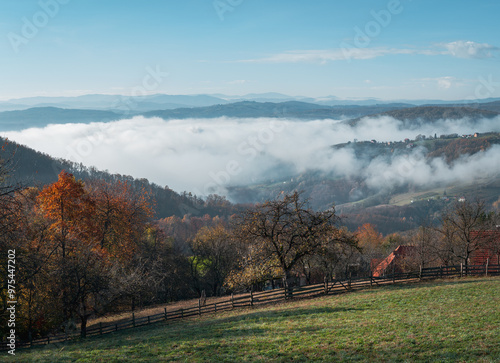 Fog in a valley with forest, hills and mountains during autumn morning