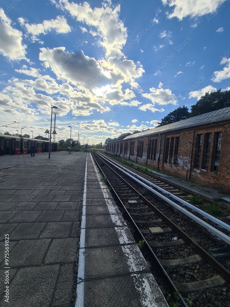 Fototapeta premium Blick auf Bahngleise mit einem alten, zerfallenen Gebäude und einem wolkigen Himmel in Bernau bei Berlin (Brandenburg)