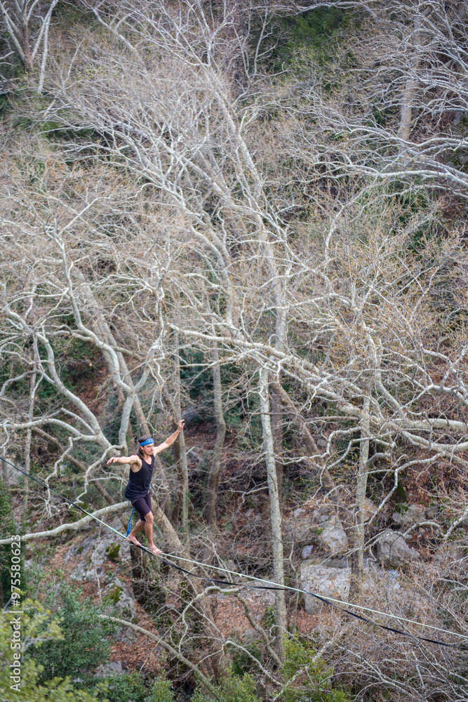 Naklejka premium A tightrope walker walks along a cable stretched over a canyon.