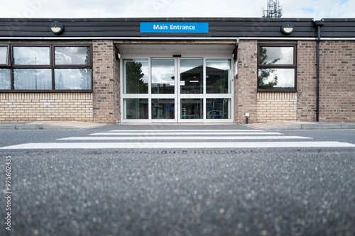 Quadro su tela Ground level view of a patient zebra crossing leading to the entrance of a typical NHS hospital in Britain