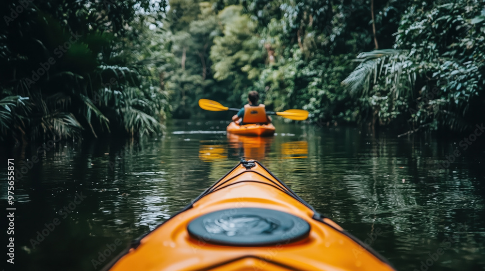 Fototapeta premium A person kayaking on tranquil river surrounded by lush greenery