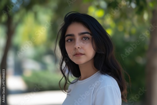 A close-up portrait of a young Pakistani woman wearing a casual t-shirt, with a blurred background.