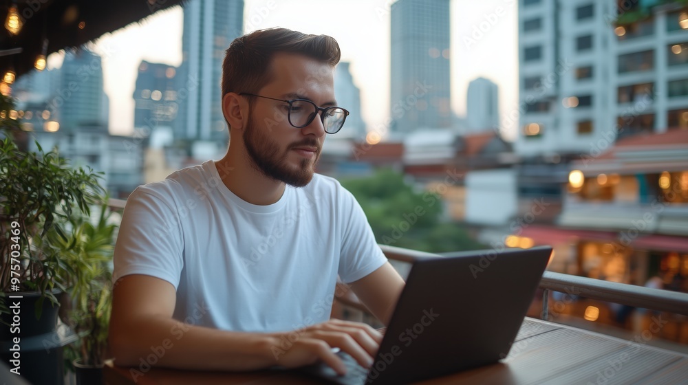 Man typing on laptop at a Bangkok rooftop cafe Man typing on laptop at a Bangkok rooftop cafe