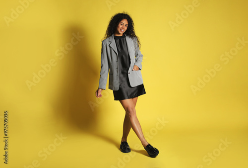 Beautiful woman in stylish jacket on yellow background