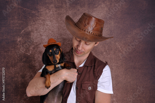 homem usando chapéu de vaqueiro com cachorro  salsicha usando chapéu photo