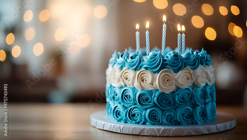 A beautifully decorated blue birthday cake with white roses and lit candles, perfect for celebrations and special occasions. photo