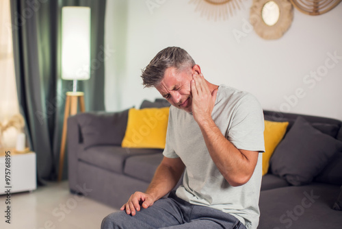 A man holding his face in pain due to a toothache. His expression reveals his suffering as he tries to alleviate the ache. People and healthcare concept