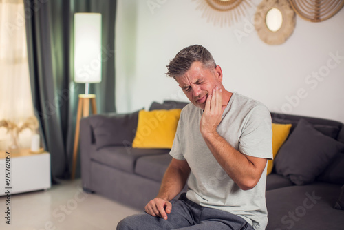 A man holding his face in pain due to a toothache. His expression reveals his suffering as he tries to alleviate the ache. People and healthcare concept photo