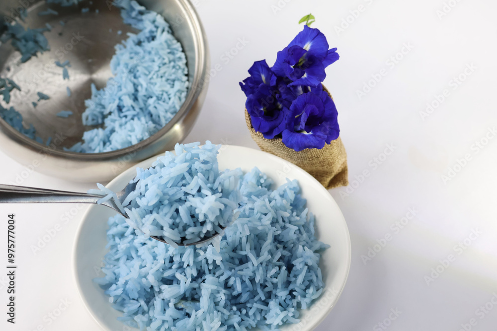Use a spoon to scoop up the blue-purple rice from the plate. Next was the purple butterfly pea flower in the bag. and a rice cooker placed on a white floor
Use a spoon to scoop up the blue-purple rice from the plate. Next was the purple butterfly pea flower in the bag. and a rice cooker placed on a white floor