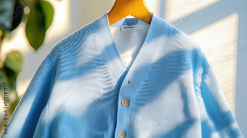 Light Blue Knit Cardigan on Wooden Hanger with Sunbeams
