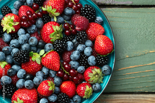 Mix of ripe colorful berries in bowl photography . Blueberry , strawberry , raspberry , blackberry and red currant . Top view photo