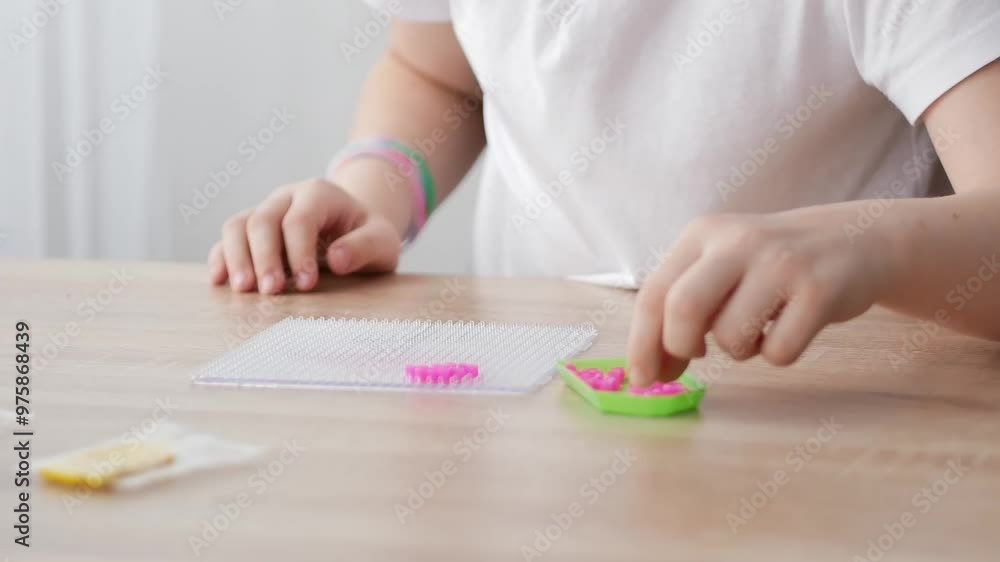 The hands of a child assembling a toy from plastic parts of a thermomosaic. The first stage of the work. Sensory education, construction of hot plastic. Close-up. The hands of a child assembling a toy from plastic parts of a thermomosaic. The first stage of the work. Sensory education, construction of hot plastic. Close-up.