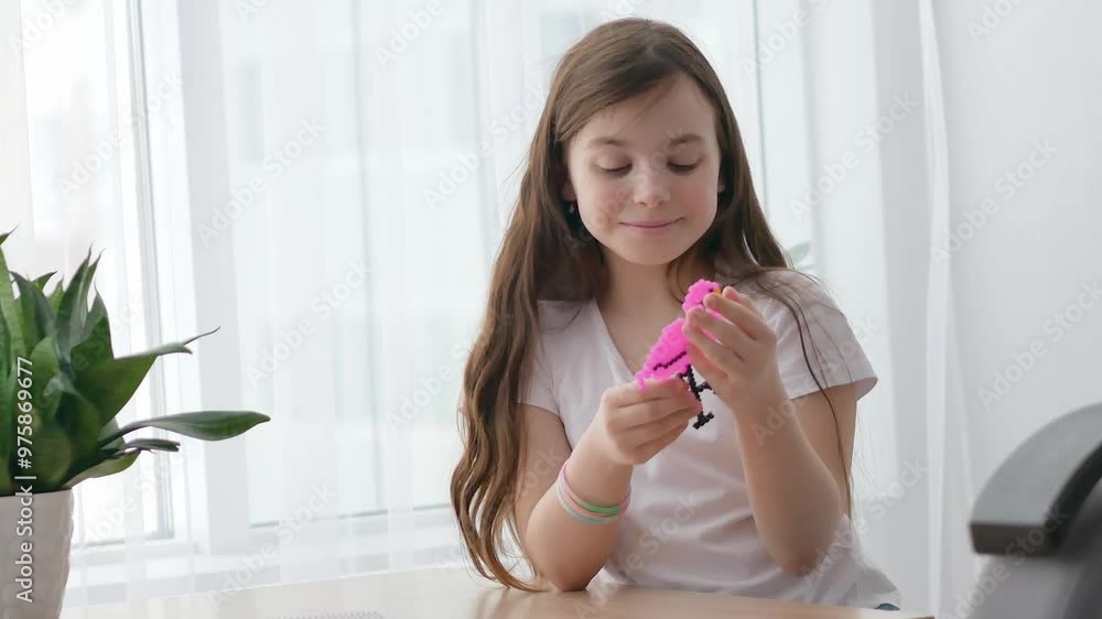 A joyful little girl looks at a pink flamingo made with her own hands from a thermoset, admires it, turns it in her hands. The fourth stage of the work. A joyful little girl looks at a pink flamingo made with her own hands from a thermoset, admires it, turns it in her hands. The fourth stage of the work.