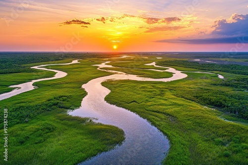 A peaceful river delta with winding waterways surrounded by lush green marshland, under a vibrant sunset sky.