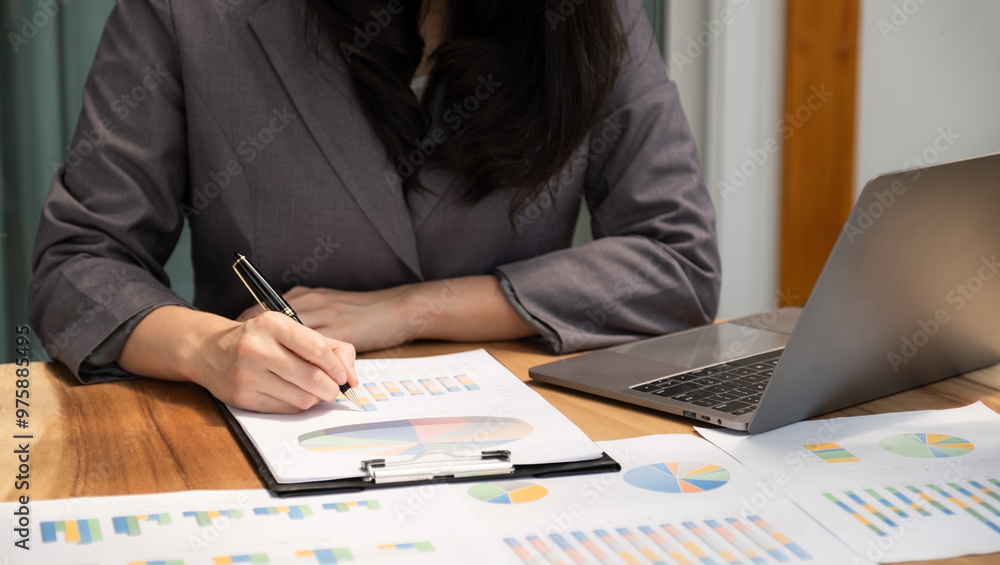 Businesswoman hand holding pen, analysis the graph with laptop at the home office for setting challenging business goals And planning to achieve the new target Businesswoman hand holding pen, analysis the graph with laptop at the home office for setting challenging business goals And planning to achieve the new target