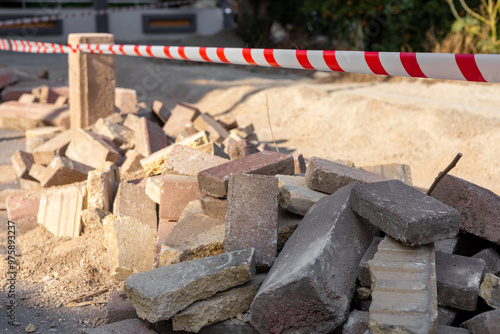 Construction site with a pile of bricks and caution tape marking the area for safety photo