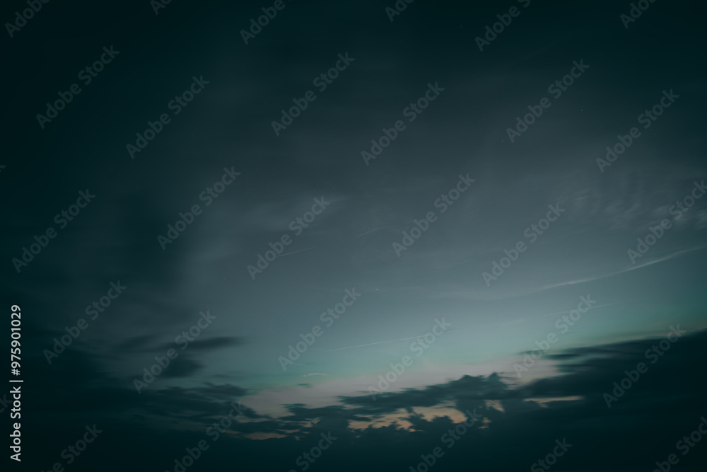 A moody twilight scene showcasing a dark sky with soft cloud silhouettes. The fading light on the horizon provides a subtle glow, adding a calm yet mysterious atmosphere to the composition.