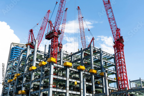 Obraz na płótnie Low-angle view of cranes and steel structures of building construction with a blue sky background in Taiwan. w salonie