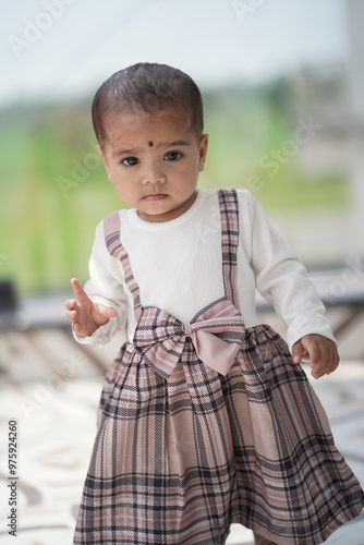 Adorable Baby Outdoors, Toddler in Plaid Dress, Stylish Toddler Outfit, Cute Girl Standing, Plaid Fashion for Kids, Baby Girl in Bow Dress, Child Walking Barefoot Stock Photo.






 photo