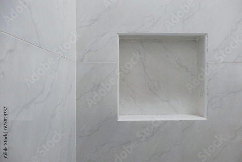 Close up of empty built-in shower caddy in wall recess in bathroom. Modern elegant bathroom interior with marble wall tiles. Display shelf for toiletries logo branding mockup