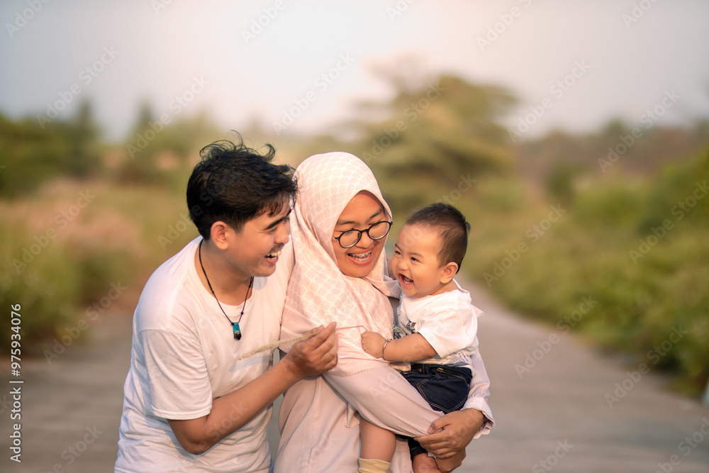 A family that looks happy with lots of laughter with mother, father and baby boy. they laughed while teasing the baby boy. father and mother smile seeing the baby boy. photo atmosphere in nature. A family that looks happy with lots of laughter with mother, father and baby boy. they laughed while teasing the baby boy. father and mother smile seeing the baby boy. photo atmosphere in nature.