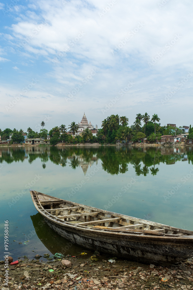 Traditional Bengali Wooden boat on pond bank Shiva Temple, at Puthia Rajbari complex, in Puthia, Bangladesh.