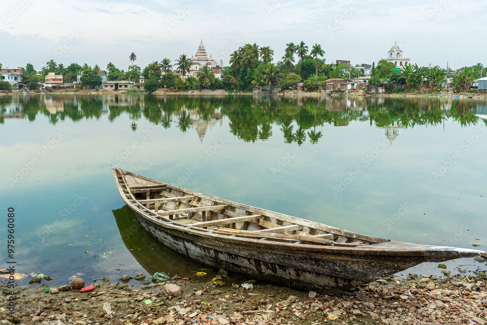 Traditional Bengali Wooden boat on pond bank Shiva Temple, at Puthia Rajbari complex, in Puthia, Bangladesh. Pancha Ratna Shiva Temple.