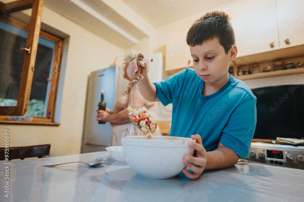 Young boy in blue shirt carefully mixing a healthy salad in the kitchen. Emphasizes family bonding, cooking skills, and nutrition in a homely environment. Young boy in blue shirt carefully mixing a healthy salad in the kitchen. Emphasizes family bonding, cooking skills, and nutrition in a homely environment.
