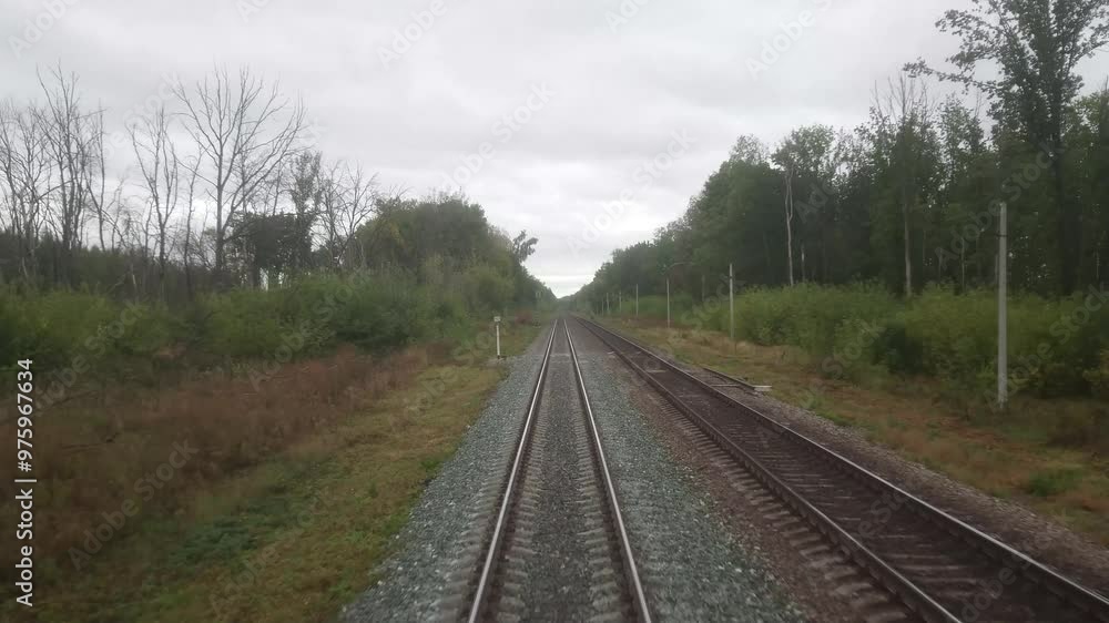 Video shooting through the windshield of the train driver's cabin. Moving forward. The Russian Railway. An autumn cloudy day, green trees. Video shooting through the windshield of the train driver's cabin. Moving forward. The Russian Railway. An autumn cloudy day, green trees.