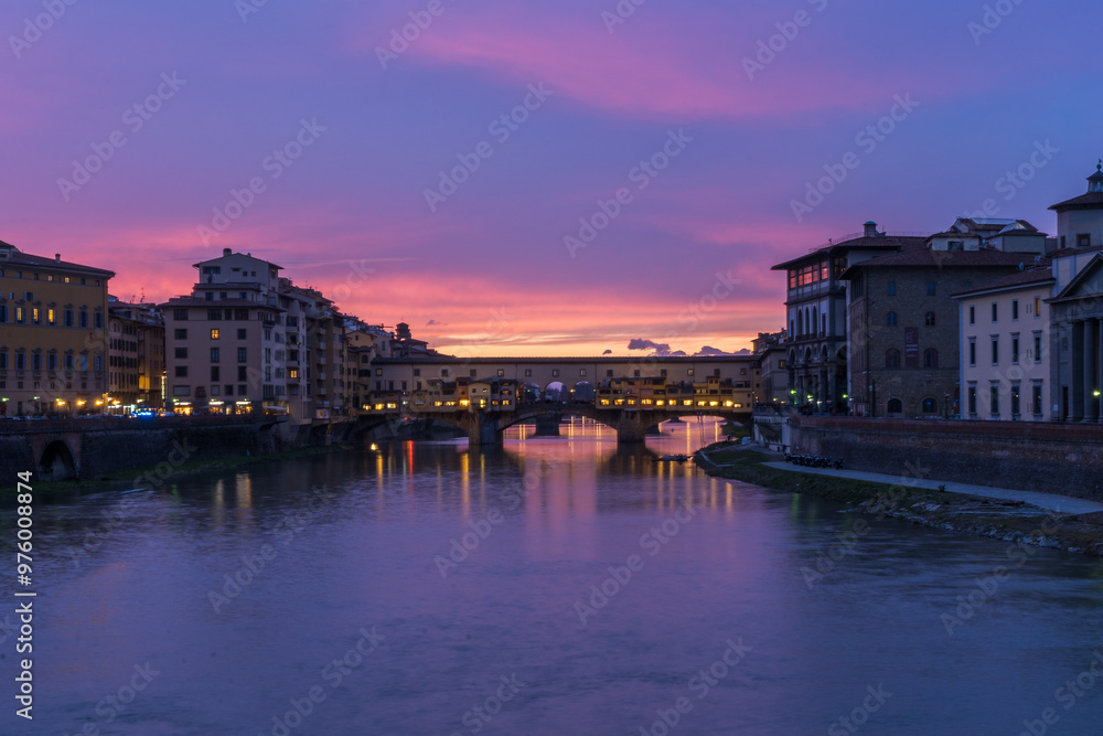 View of the iconic Ponte Vecchio over the Arno River at dusk in Florence, Italy. View of the iconic Ponte Vecchio over the Arno River at dusk in Florence, Italy.