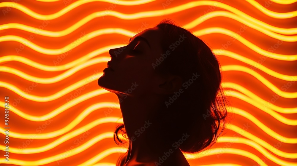 Woman's silhouette against a backdrop of wavy orange neon lights Woman's silhouette against a backdrop of wavy orange neon lights
