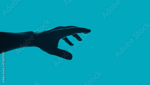 Reaching and grab. Desire to achieve. Dark hand on a blue green backdrop. Seek out something.