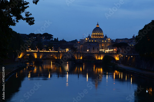  Castel Sant'Angelo in Rome, beautifully illuminated and reflecting on the calm river. The dark blue sky contrasts with the warm lights of the castle.