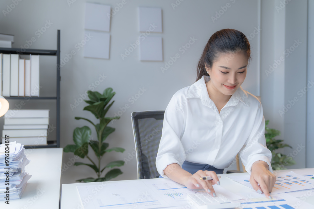 Young professional woman is feeling tired and sleepy while analyzing graphs and drinking coffee at her desk in a modern office Young professional woman is feeling tired and sleepy while analyzing graphs and drinking coffee at her desk in a modern office