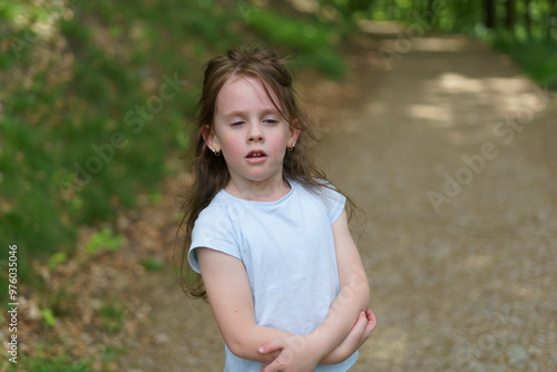 Little beautiful girl on the background of the road in the park. Happy childhood concept outdoors