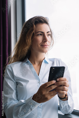 Female with phone looking away in window