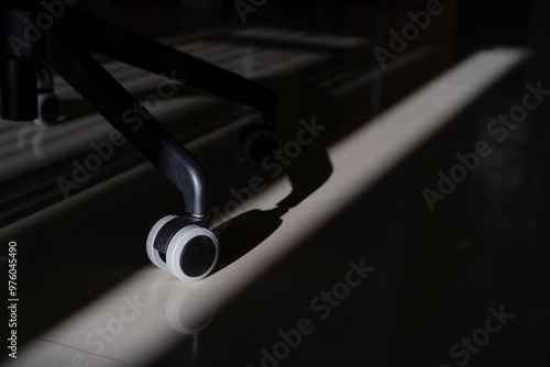 Close up of office chair caster wheel illuminated by sunlight.