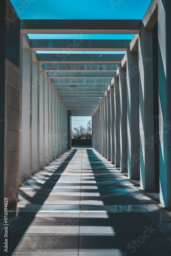 A stunning architectural corridor featuring series of vertical columns casting dramatic shadows on ground, creating captivating interplay of light and structure