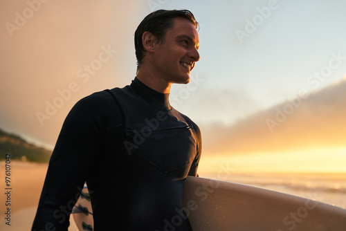 A smiling man in a wetsuit holding a surfboard on the beach during a beautiful sunset. Perfect image capturing joy, surfing, and the beauty of nature.