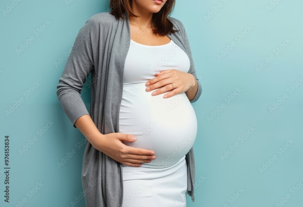 A pregnant woman in a white dress and gray cardigan, with her hands on her belly, stands against a light blue background, gazing off to the side, creating a serene and contemplative atmosphere A pregnant woman in a white dress and gray cardigan, with her hands on her belly, stands against a light blue background, gazing off to the side, creating a serene and contemplative atmosphere