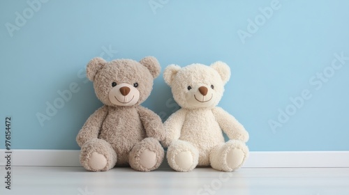 Two teddy bears sitting on floor near blue wall