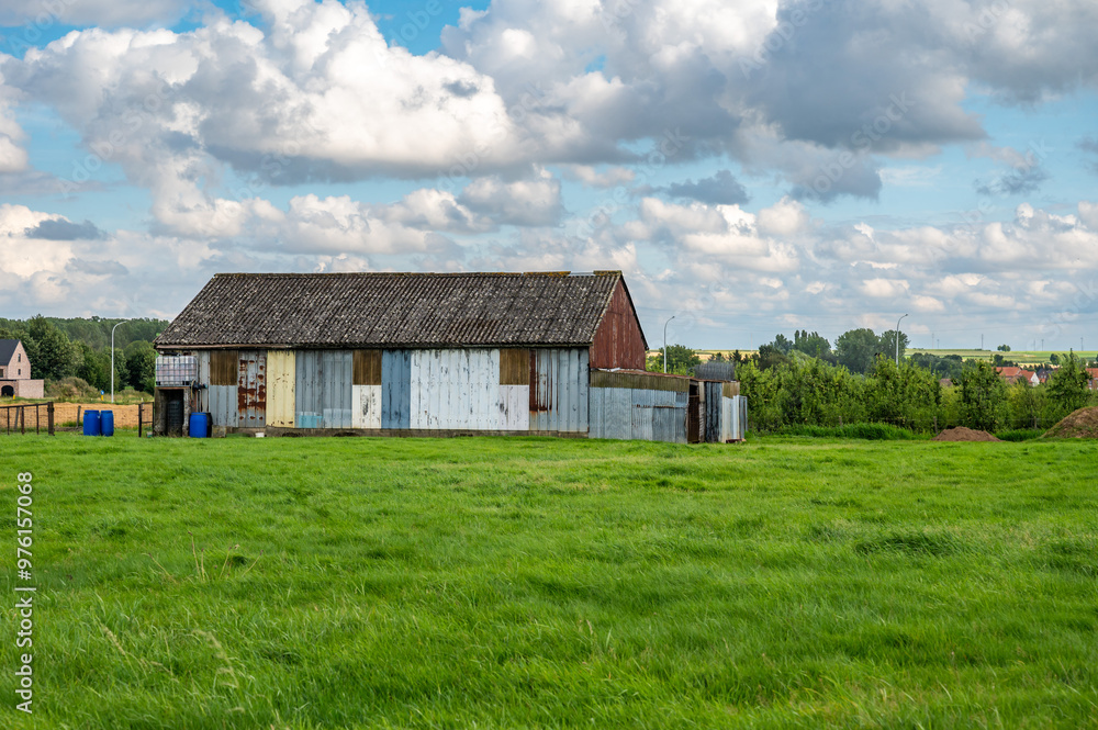 Fototapeta premium Metal plated colorful farmer shed and green meadows at the Flemish countryside in Linter, belgium