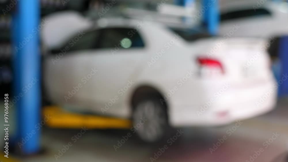 Blurred image of white car being serviced in auto repair shop, showcasing maintenance and repair activities in professional garage. Automotive Services and Maintenance. Blurred image of white car being serviced in auto repair shop, showcasing maintenance and repair activities in professional garage. Automotive Services and Maintenance.