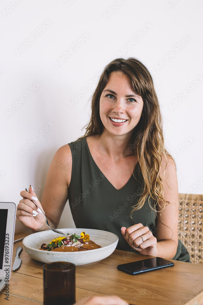 Portrait of positive female freelancer enjoying break time for healthy lunch sittin at cafeteria table with fresh salad and laptop computer with mockup area and smiling at camera, nutrition Portrait of positive female freelancer enjoying break time for healthy lunch sittin at cafeteria table with fresh salad and laptop computer with mockup area and smiling at camera, nutrition