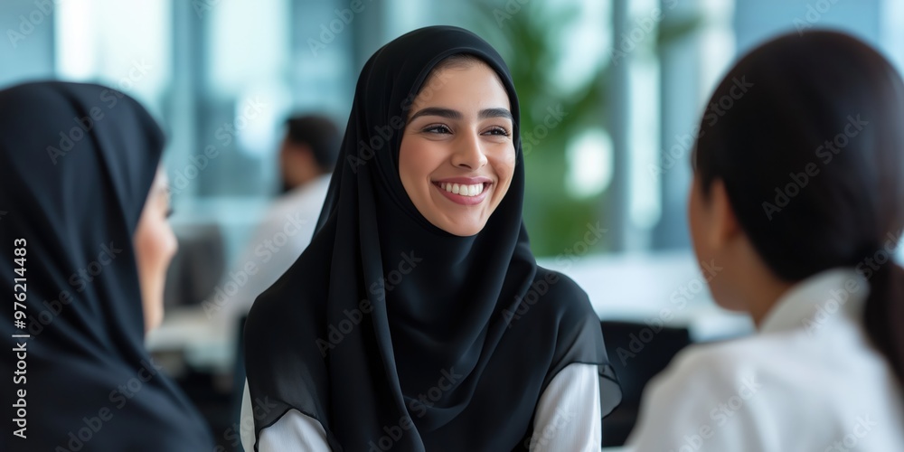 Happy positive female colleagues from the Middle East joking and laughing during a coffee break in the workplace Happy positive female colleagues from the Middle East joking and laughing during a coffee break in the workplace