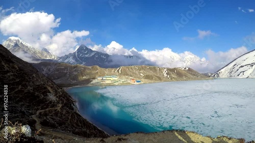 Panoramic view on Gokyo mountain valley with ice partly covered Gokyo lake and Gokyo village in Nepal in Himalayas on height 4750 meters in a sunny day. Time lapse video. Landscapes theme