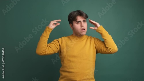 Upset man making blah blah gesture in green studio photo